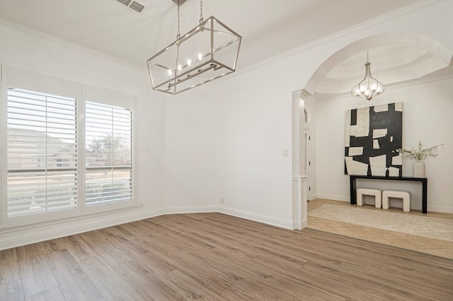 unfurnished dining area featuring arched walkways, crown molding, a raised ceiling, wood finished floors, and a chandelier