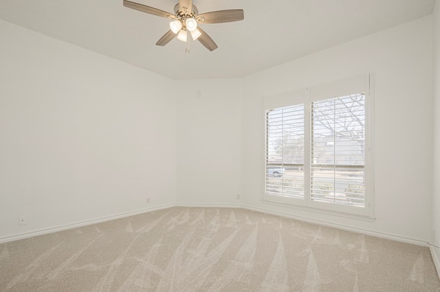 empty room featuring light colored carpet, ceiling fan, and baseboards