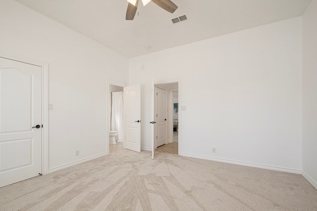 unfurnished bedroom with light colored carpet, visible vents, ensuite bathroom, a ceiling fan, and baseboards