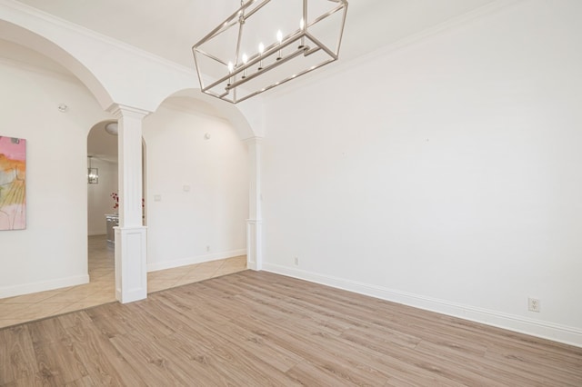 empty room with arched walkways, crown molding, light wood-type flooring, and ornate columns