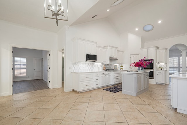 kitchen with light tile patterned floors, appliances with stainless steel finishes, white cabinets, and arched walkways