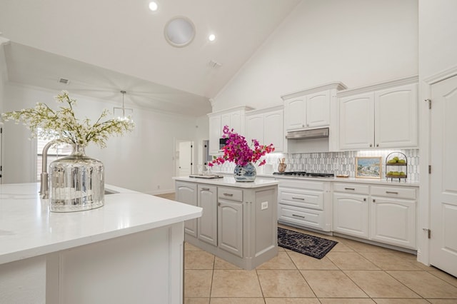 kitchen with stainless steel gas cooktop, light countertops, white cabinets, a kitchen island, and under cabinet range hood