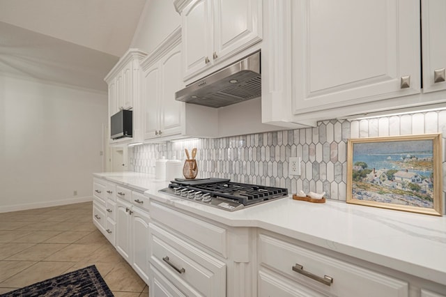 kitchen featuring light tile patterned floors, decorative backsplash, stainless steel gas cooktop, under cabinet range hood, and white cabinetry