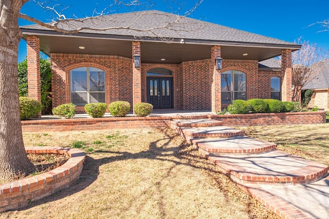 doorway to property with a shingled roof, french doors, and brick siding