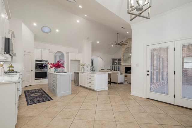 kitchen with light countertops, open floor plan, white cabinetry, and a center island with sink