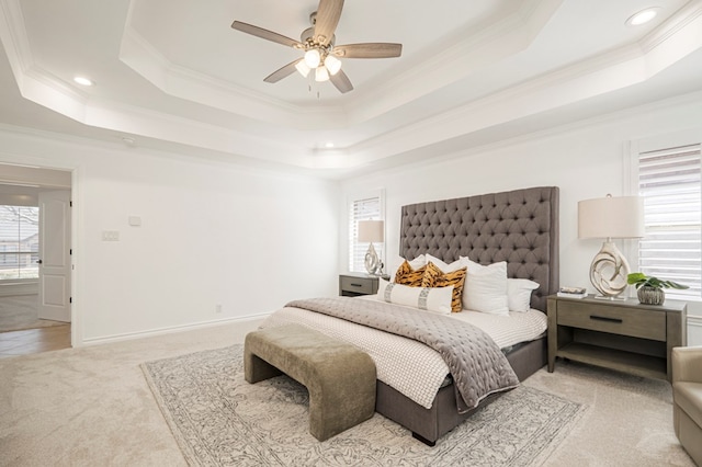 bedroom with a tray ceiling, multiple windows, crown molding, and light carpet