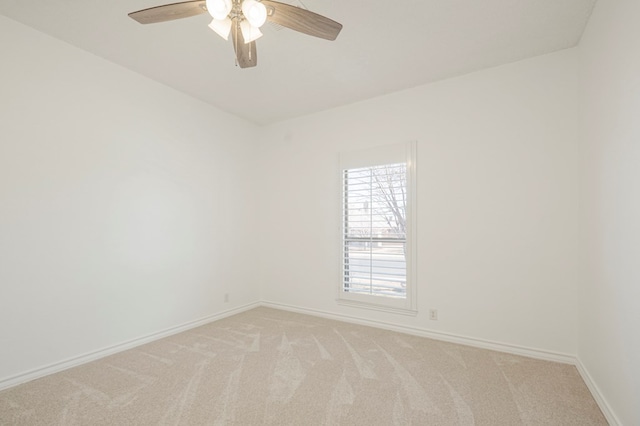 unfurnished room with baseboards, a ceiling fan, and light colored carpet