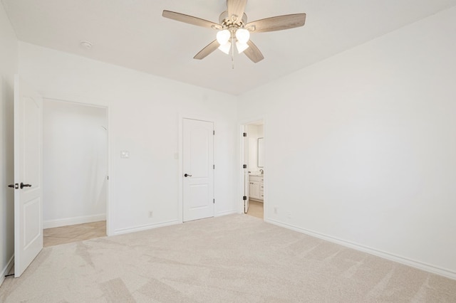 unfurnished bedroom with baseboards, ensuite bath, a ceiling fan, and light colored carpet