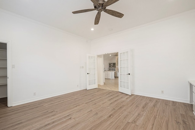 empty room with baseboards, french doors, light wood-type flooring, and crown molding