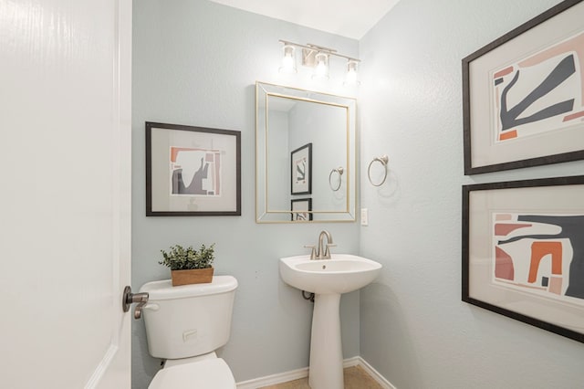 half bathroom featuring toilet and baseboards