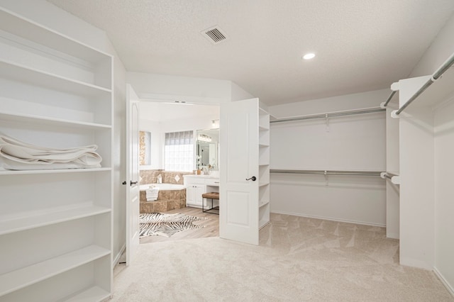 walk in closet featuring visible vents and light colored carpet