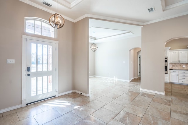 foyer with ornamental molding, an inviting chandelier, and a tray ceiling