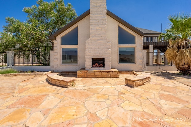 rear view of house with a patio area and an outdoor fireplace