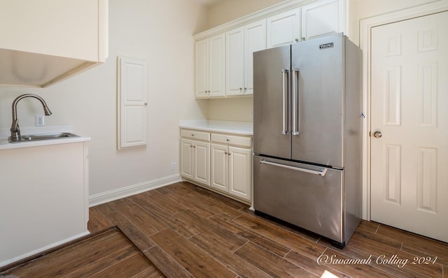 kitchen featuring dark hardwood / wood-style flooring, white cabinetry, high quality fridge, and sink