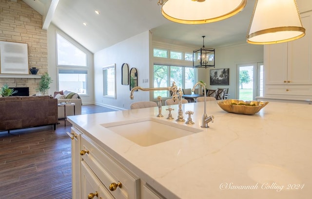 kitchen with light stone countertops, hanging light fixtures, dark hardwood / wood-style flooring, a fireplace, and white cabinets