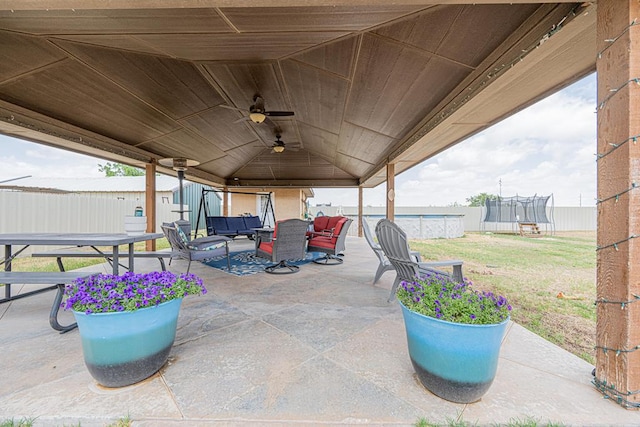 view of patio with a trampoline, a gazebo, ceiling fan, fence, and an outdoor living space