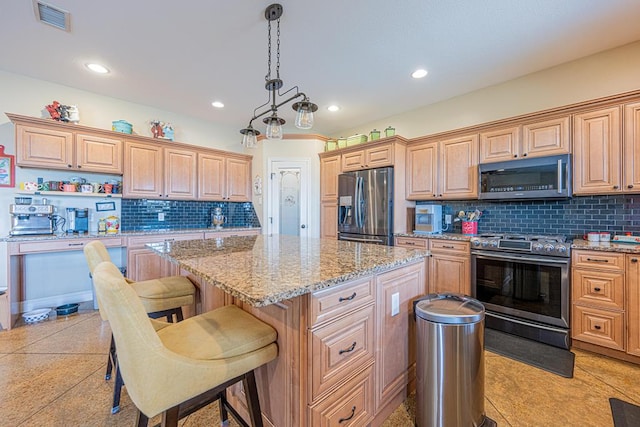 kitchen with light stone counters, decorative backsplash, appliances with stainless steel finishes, visible vents, and a center island