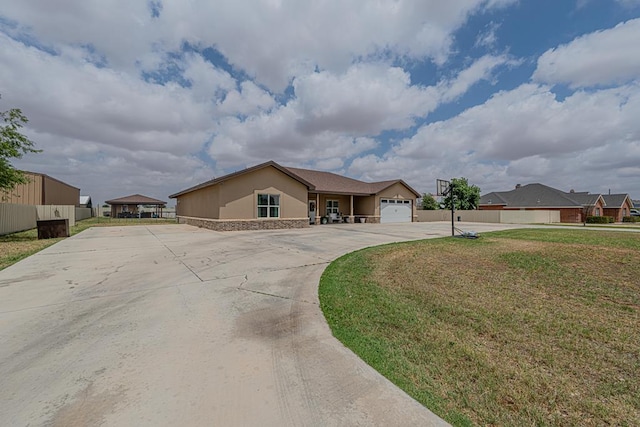ranch-style home featuring stucco siding, fence, curved driveway, stone siding, and a front lawn