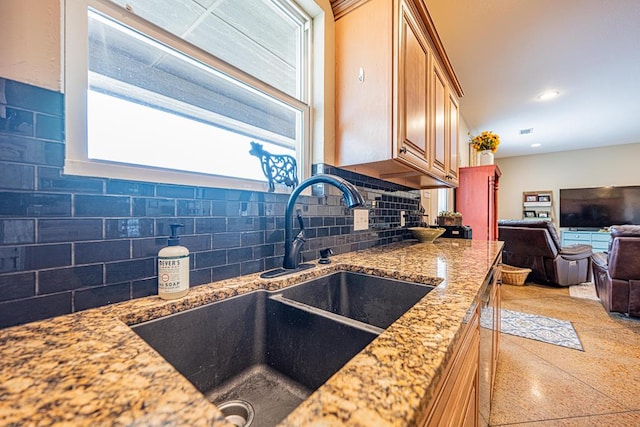kitchen with recessed lighting, light stone countertops, a sink, decorative backsplash, and open floor plan