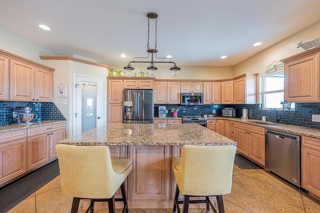 kitchen featuring a kitchen breakfast bar, tasteful backsplash, a sink, appliances with stainless steel finishes, and a center island