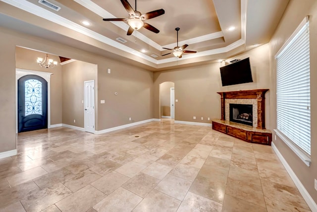 unfurnished living room featuring ornamental molding, a raised ceiling, and ceiling fan with notable chandelier