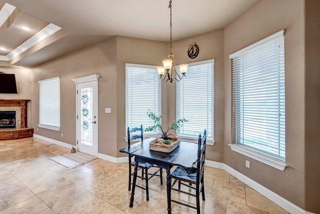 dining space featuring an inviting chandelier, a stone fireplace, light tile patterned floors, and a wealth of natural light