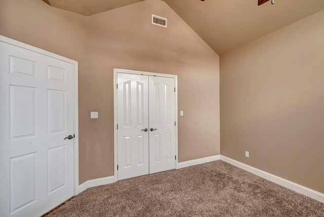 unfurnished bedroom featuring carpet floors, high vaulted ceiling, and a closet