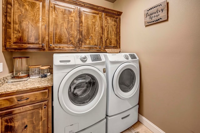 clothes washing area with separate washer and dryer and cabinets