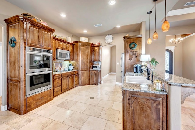 kitchen with appliances with stainless steel finishes, a breakfast bar, sink, hanging light fixtures, and kitchen peninsula