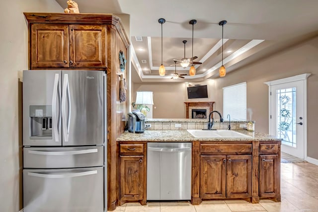 kitchen with sink, hanging light fixtures, ceiling fan, a tray ceiling, and stainless steel appliances