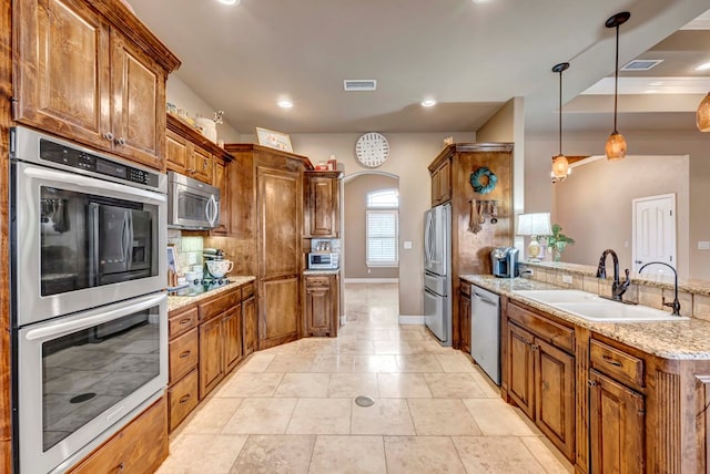 kitchen with decorative light fixtures, sink, decorative backsplash, stainless steel appliances, and light stone countertops