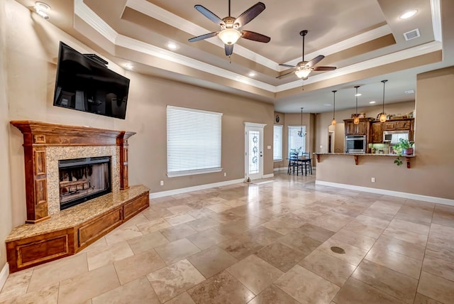 unfurnished living room with ornamental molding, ceiling fan, a high end fireplace, and a tray ceiling