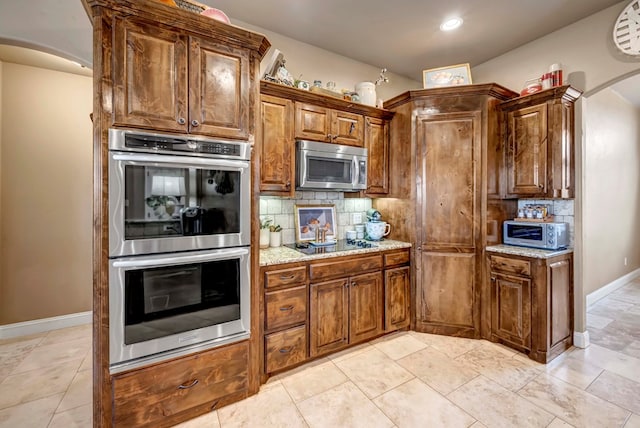 kitchen featuring tasteful backsplash, light stone countertops, light tile patterned floors, and stainless steel appliances