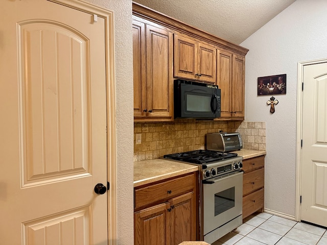 1322 Dormard Ave, Midland, TX 79705 - kitchen featuring black microwave, stainless steel gas range oven, brown cabinets, decorative backsplash, and light countertops