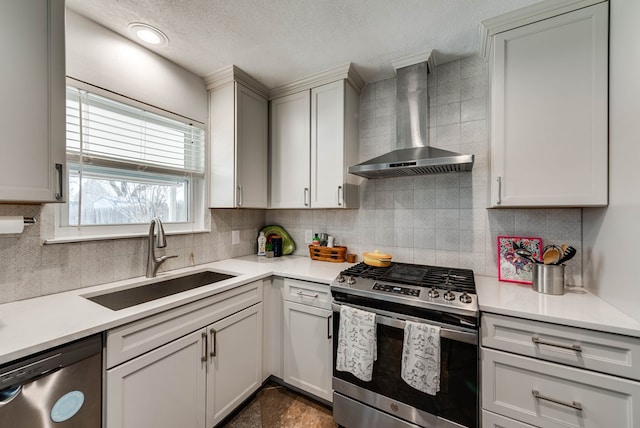 kitchen featuring a sink, light countertops, wall chimney range hood, appliances with stainless steel finishes, and decorative backsplash