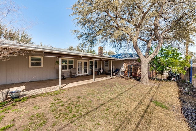 rear view of house with french doors, a chimney, fence, a yard, and a patio area