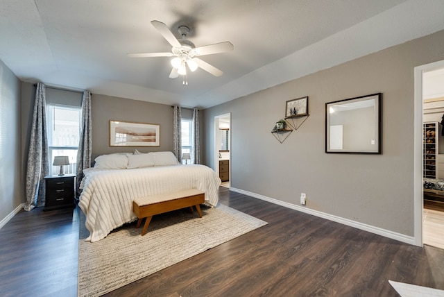 bedroom with dark wood-type flooring, ceiling fan, baseboards, and ensuite bathroom