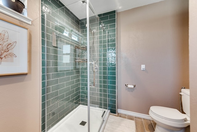 full bath featuring a stall shower, baseboards, toilet, and wood tiled floor