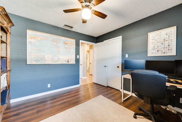 office with dark wood-style floors, visible vents, a ceiling fan, a textured ceiling, and baseboards