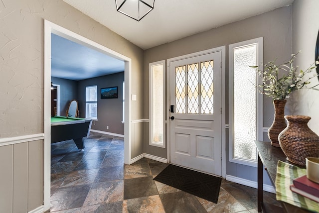 foyer featuring stone finish flooring, billiards, and baseboards