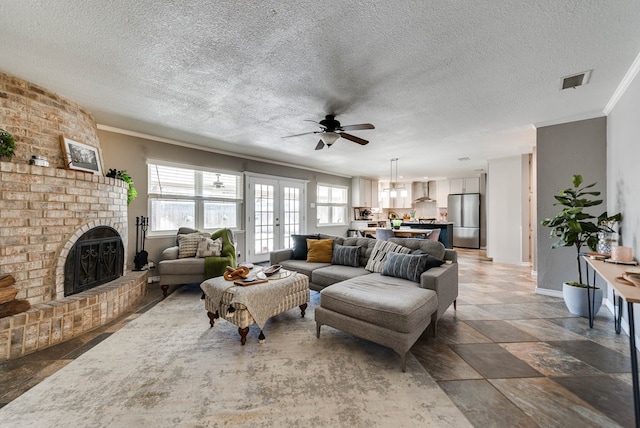 living room with baseboards, visible vents, a textured ceiling, crown molding, and a brick fireplace