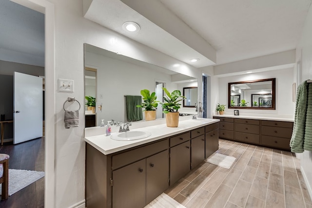 bathroom with wood tiled floor, a sink, recessed lighting, and double vanity