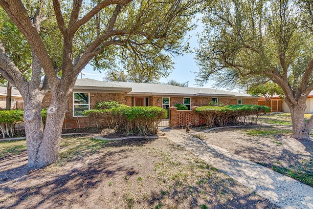 ranch-style home with a fenced front yard and brick siding