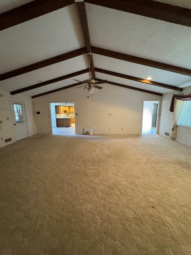 unfurnished living room with lofted ceiling with beams, a textured ceiling, and carpet flooring