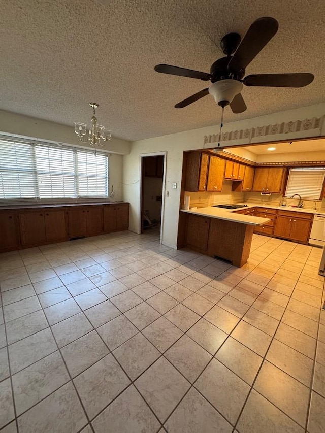 kitchen with a textured ceiling, a peninsula, light countertops, and a notable chandelier