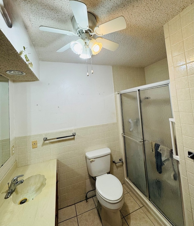 full bath with tile patterned floors, tile walls, a shower stall, and a ceiling fan
