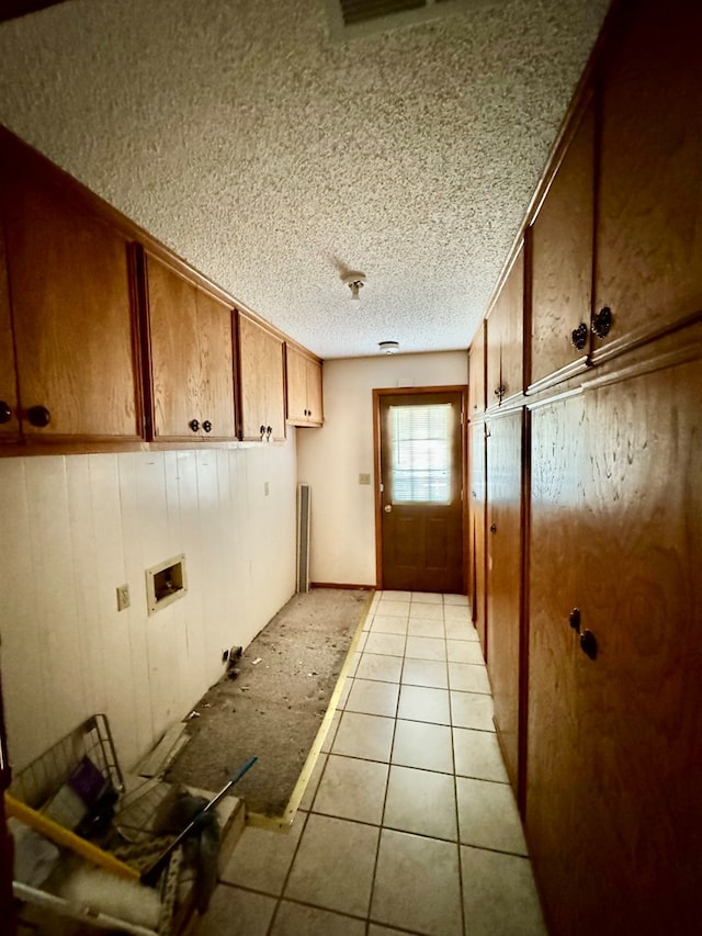 interior space with brown cabinetry, a textured ceiling, and light tile patterned floors