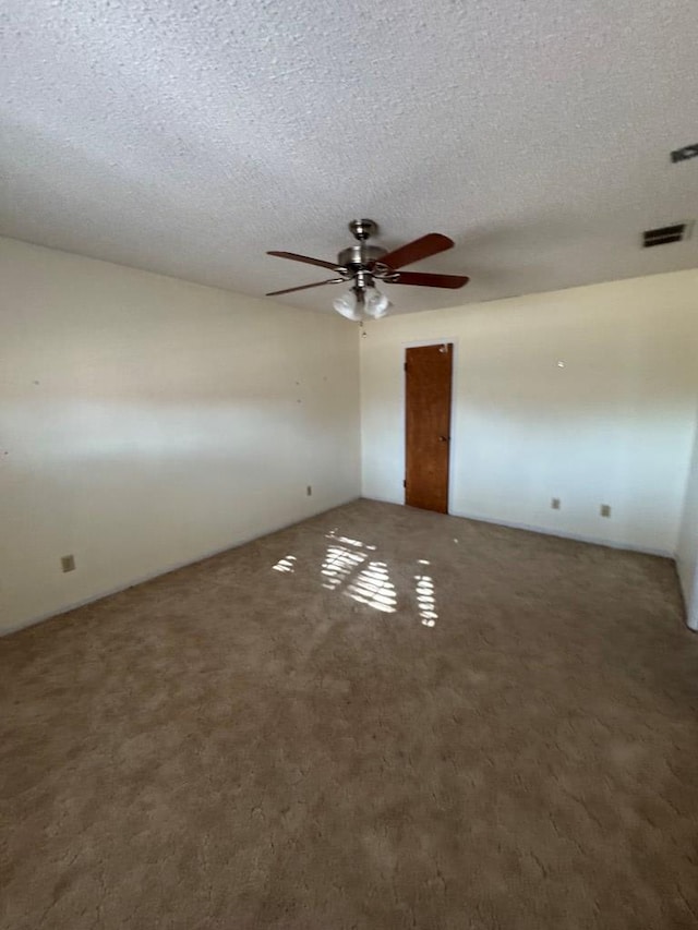 carpeted spare room with visible vents, ceiling fan, and a textured ceiling