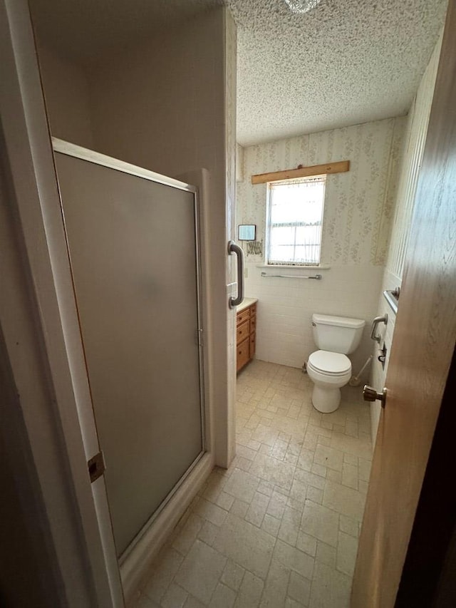 full bath featuring a textured ceiling, a stall shower, toilet, and wallpapered walls