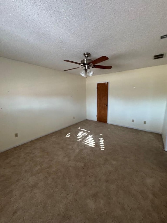 empty room featuring carpet, visible vents, ceiling fan, and a textured ceiling